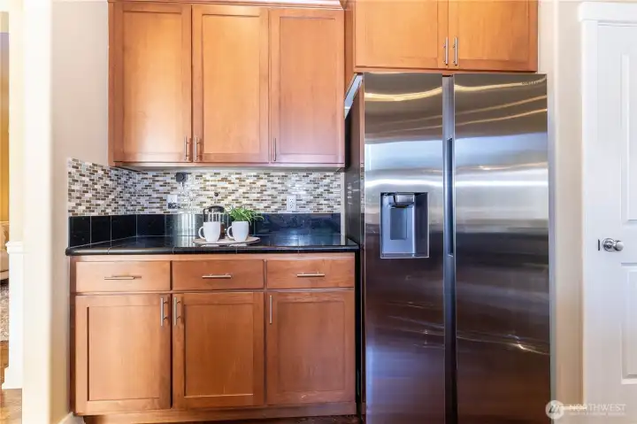 Convenient beverage station beside the refrigerator—perfect for morning coffee or evening wine. Coordinated backsplash and cabinetry tie in with the kitchen’s upscale finishes.
