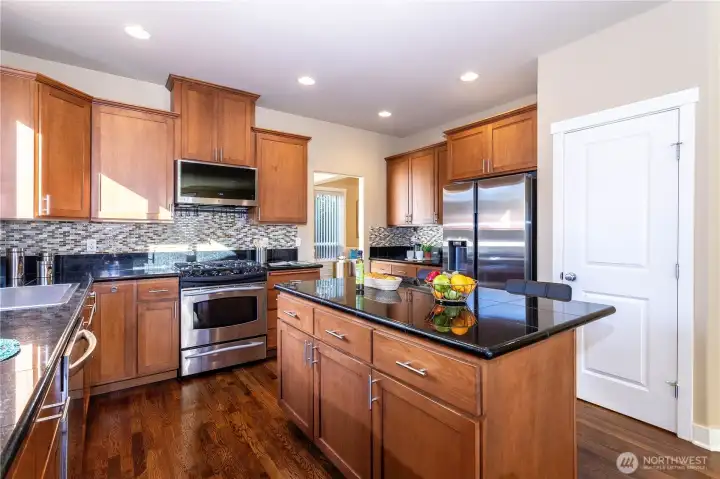 Beautifully appointed kitchen with full stainless-steel suite, gas range, and custom backsplash. Ample cabinetry and a walk-in pantry make this space as practical as it is stylish.