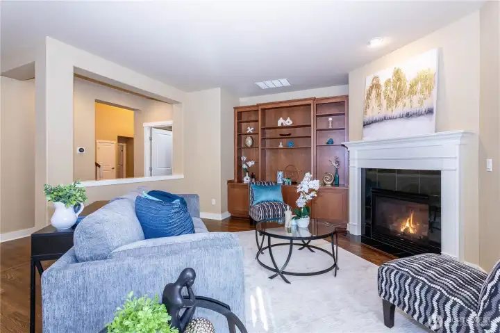 Shows how the open design integrates the family room with nearby spaces. Built-ins, fireplace, and sightlines to the foyer give this area both warmth and connectivity.