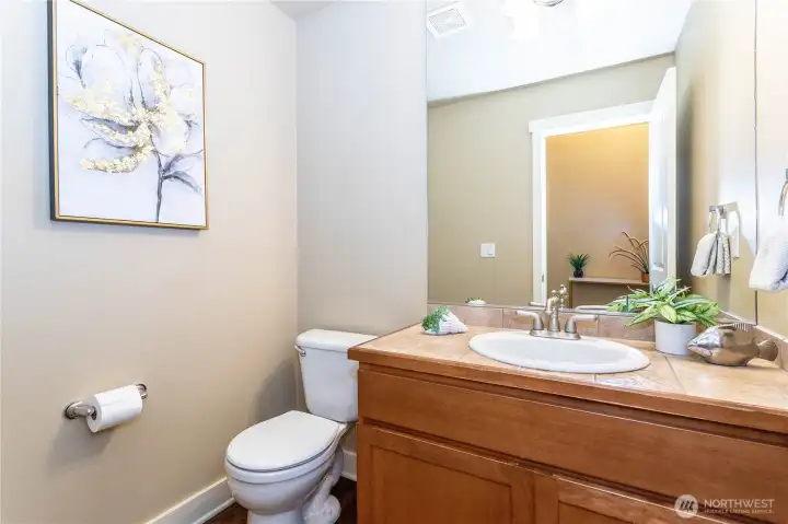 Conveniently located on the main level, the powder room features a tile countertop vanity, framed mirror, and updated fixtures. Soft wall tones and accent décor make it both functional and welcoming—perfect for guests and family alike.