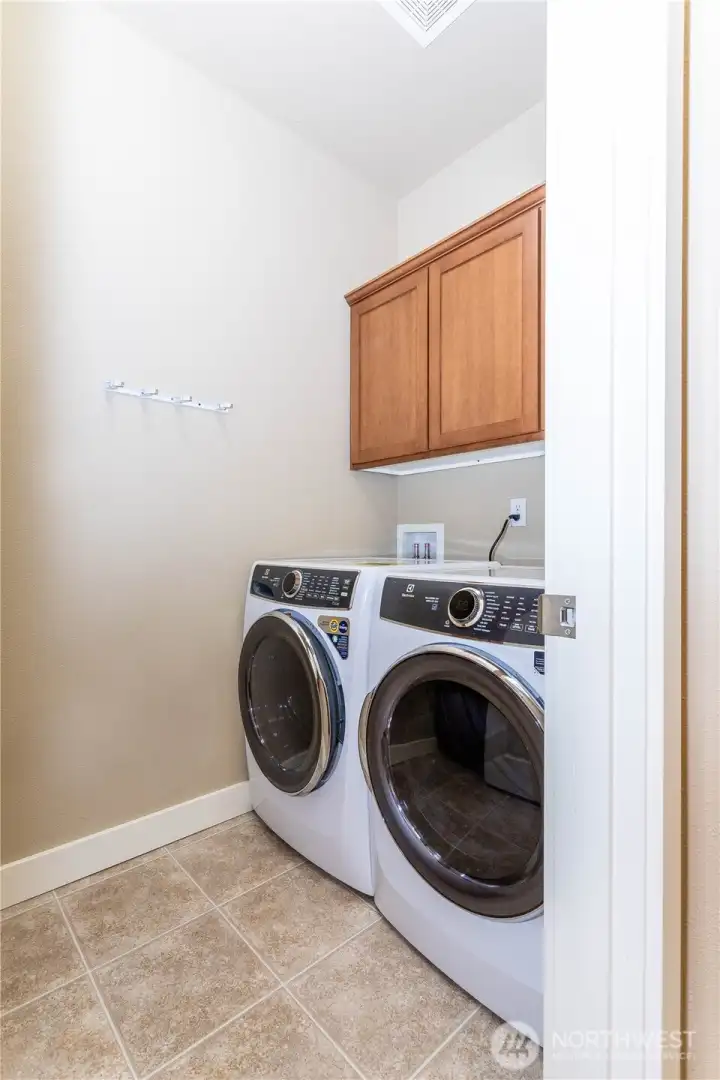 Convenient main-floor laundry with Vinyl floors, overhead cabinets, and space for full-size front-loading washer and dryer. The layout offers easy access from the living area while keeping noise away from main rooms. Clean lines and neutral colors make it simple to organize and maintain daily chores.