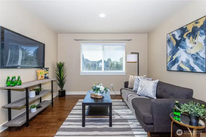 The spacious upstairs loft offers a versatile retreat for movie nights, gaming, or a home gym. Natural light pours through wide windows, and rich hardwood floors flow throughout. Neutral walls provide flexibility for any style, while recessed lighting and open layout make this loft an inviting space for everyone.