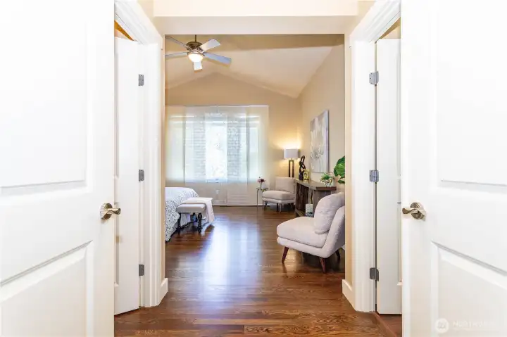 Double doors open to a spacious primary suite with vaulted ceilings, warm natural light, and hardwood floors. A true retreat, this room easily accommodates a king bed and lounge area, offering comfort and calm at the end of the day.
