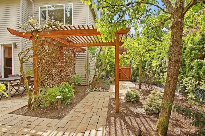 Late spring shows the beautiful wisteria trailing over the arbor, the paver pathways leading throughout both sides yards