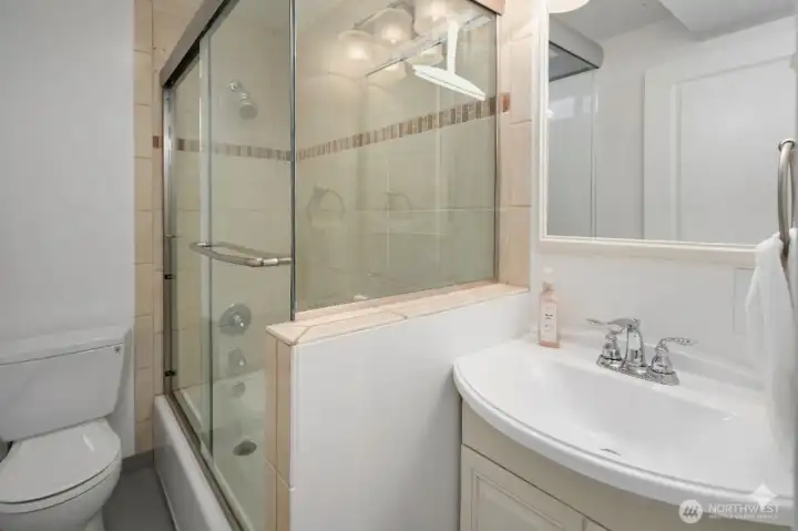 Basement bath with shower/tub and full glass enclosure.