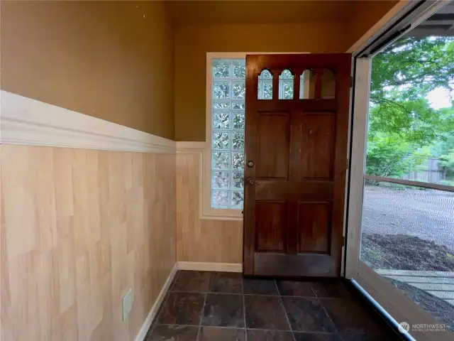 Welcoming enclosed front porch with tile flooring.