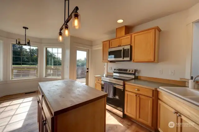 Large kitchen with stainless appliances and handy island, The breakfast nook is in the background overlooking the fenced back yard and patio.