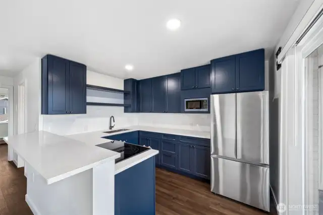 Fully renovated kitchen merges charm and top-notch materials—quartz countertops, classic subway tiles, and trendy blue cabinets that make a statement.