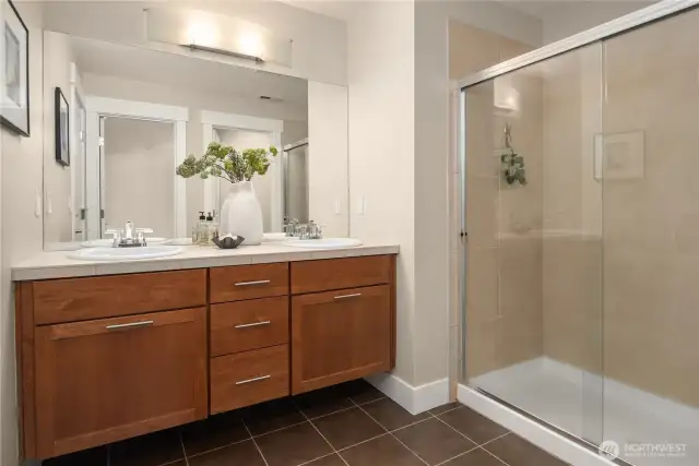 Huge primary en suite bath with double sinks, tiled floors and a tiled shower surround.
