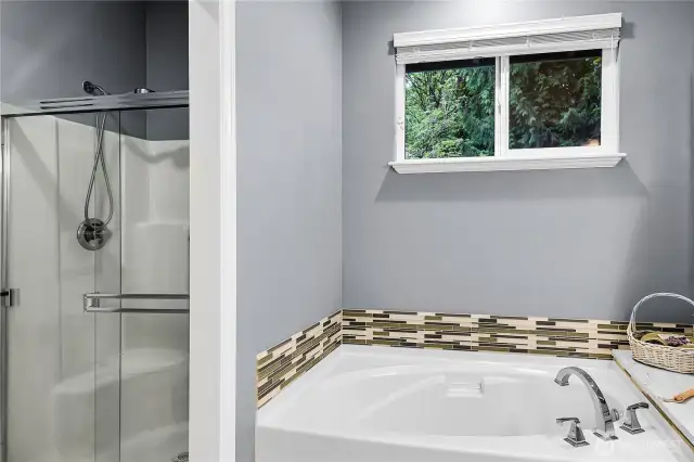 Oval soaking tub with Mosaic glass tile accented backsplash and Quartz counter and window above with two-inch blinds and screen. Paneled Quaker pocket door to watercloset and shower privacy room. Elongated watercloset. Step-in shower with glass doors, handheld shower wand.