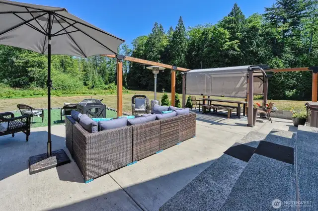 The back patio with a view of the backyard gently sloping down to the woods.