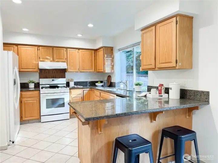 Well-appointed kitchen with granite countertops, oak cabinetry, and a breakfast bar.
