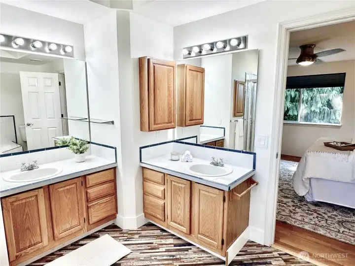 Master suite vanity area with dual sinks, ample oak cabinetry storage, and Hollywood-style lighting - your own personal spa space.