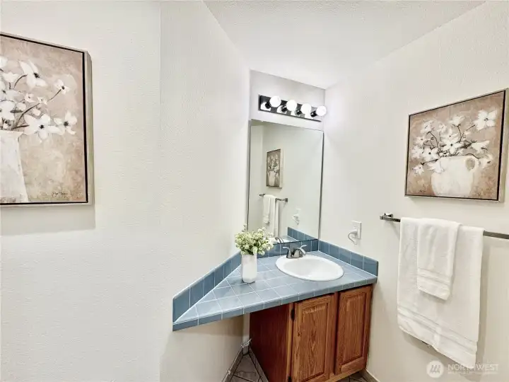 Convenient powder room on the main floor features a unique corner vanity and warm wood cabinetry - perfect for guests.