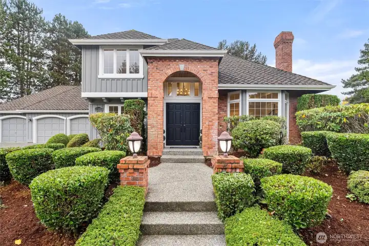 Grand front entry with brick surround and mature hedging creating a private, welcoming approach.