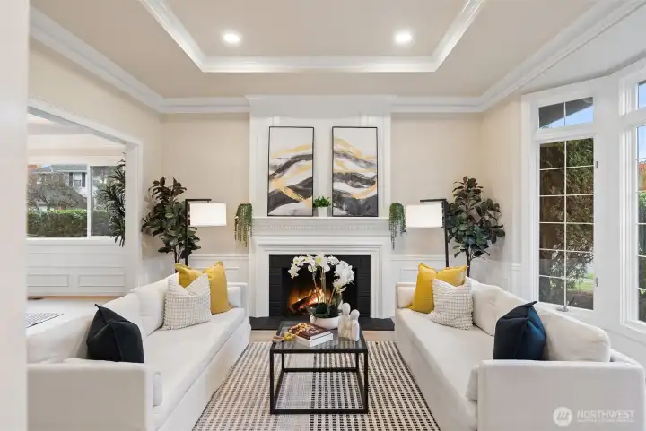 Refined formal living room with tray ceilings, fireplace, and oversized windows.