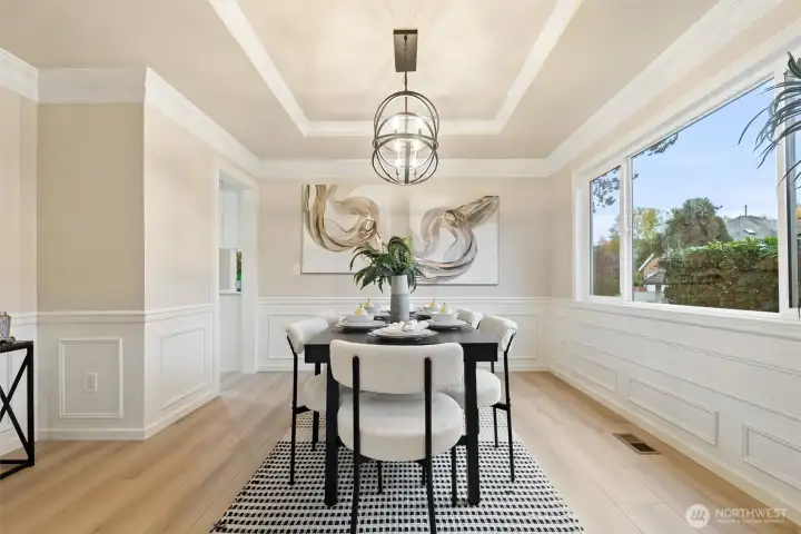 Formal dining room with coffered ceiling, statement lighting, and large picture window.