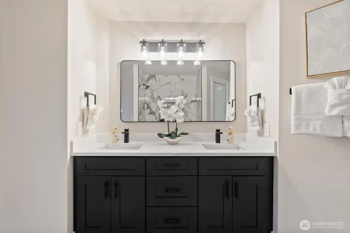 Double-sink vanity with modern lighting and quartz counters.