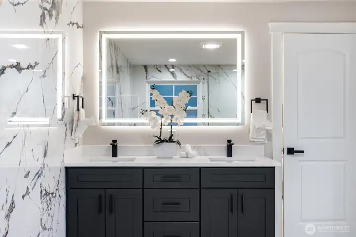 Double vanity with illuminated mirror and custom cabinetry.