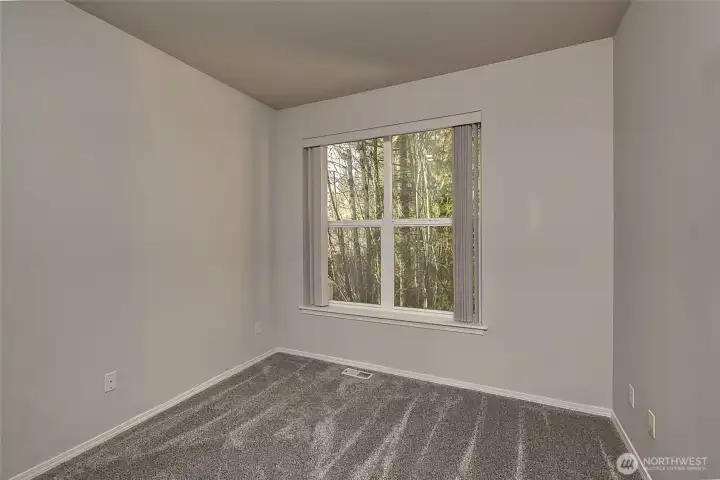Generously sized guest bedroom with tranquil wooded views.