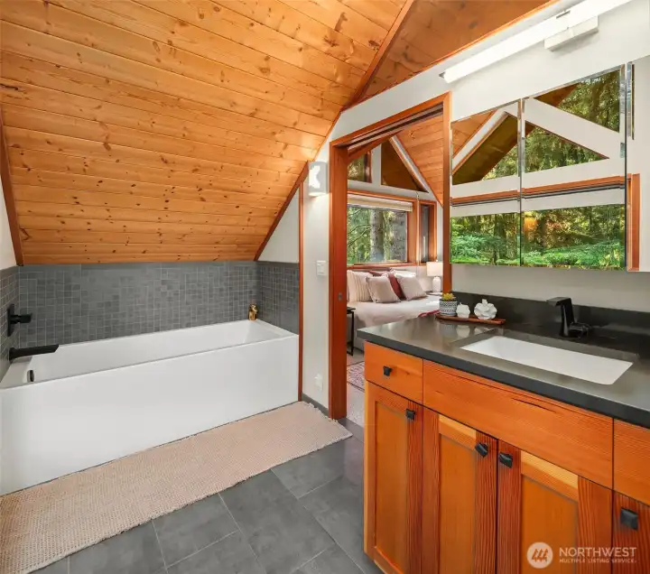 Spa-like primary bath with soaking tub and southern views out to the grounds.