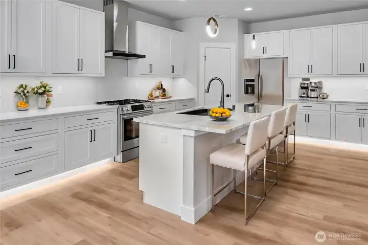Large kitchen with under-cabinet and toe-kick lighting, large pantry with shelving, and gas cooktop. Virtually staged.