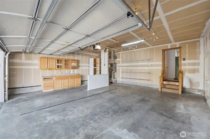 Spacious garage with built in work area and lots of lighting.