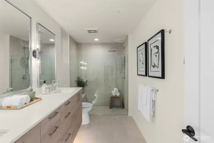 The primary bath is doing everything right—dual vanity, warm finishes, and a glass-enclosed rain shower ready for you!