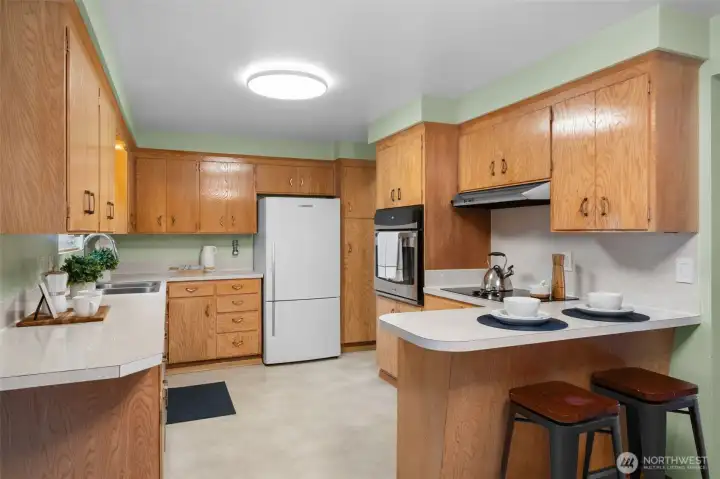 Timeless kitchen layout with generous counter space and abundant wood cabinetry for storage. A breakfast bar with seating creates a convenient spot for casual meals or morning coffee.