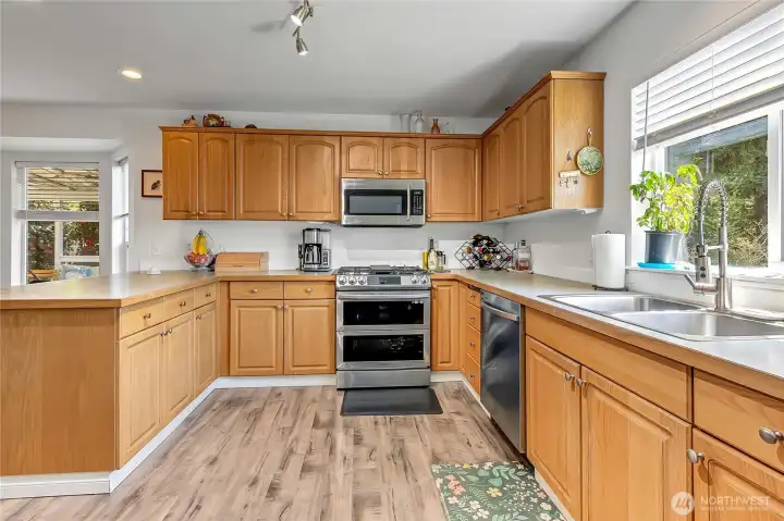 Kitchen with eating bar, ample counter space, and stainless steel appliances including range, microwave, dishwasher, and refrigerator.