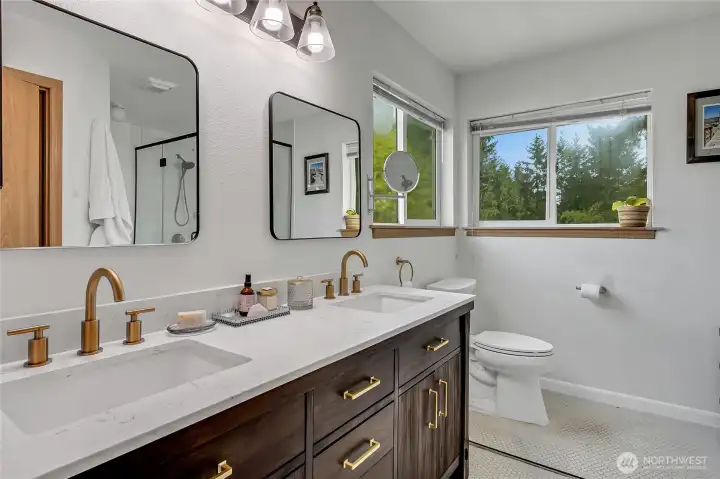emodeled primary bath with double vanity, quartz countertop, and tile flooring.
