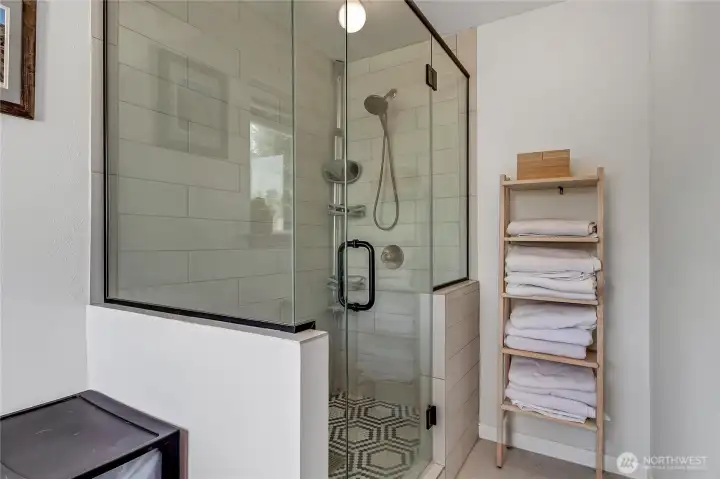 Walk-in shower with glass surround and glass door in primary bath.