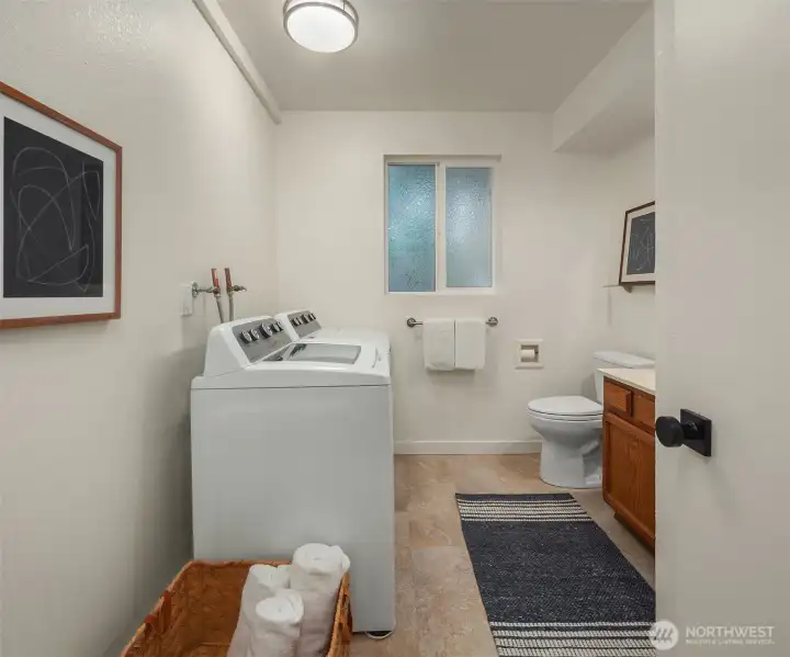 Combined laundry and 3/4 bath next to lower bedroom and garage.