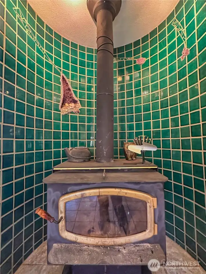 Rustic wood stove set within a stunning amethyst-inlaid tiled wall creates warmth and character