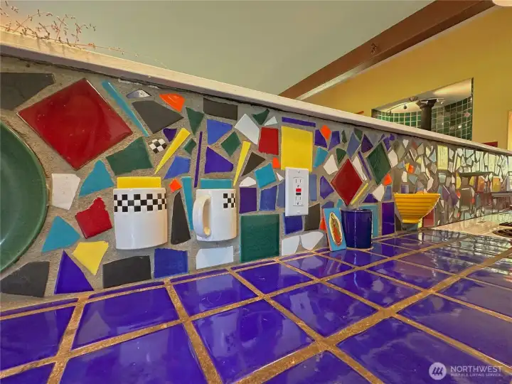 Kitchen highlights Italian-tiled countertops with a beautifully detailed mosaic backsplash for a cohesive, artisan feel