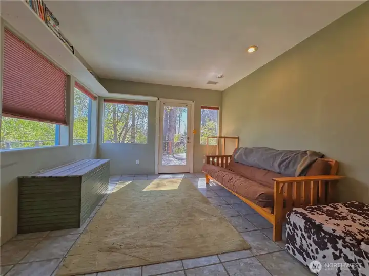 Sun-filled family room boasts wall-to-wall windows that blur the line between indoors and out, opening to a private back deck with hot tub—perfect for soaking in the tranquil landscape