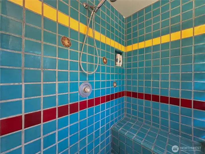 Spacious walk-in shower with bench seating, showcasing one-of-a-kind thunder egg–inlaid tilework