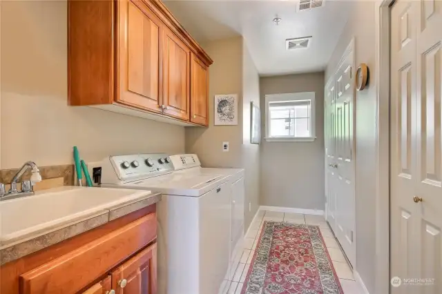 Utility Room with sink, wall mount cabinetry, 2 closets, water heater and furnace.