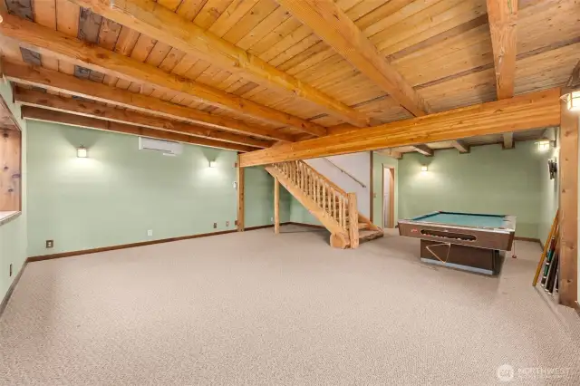 Large open bonus room with open beams, mini split, custom log staircase & room for additional storage in small room to the right of the staircase.