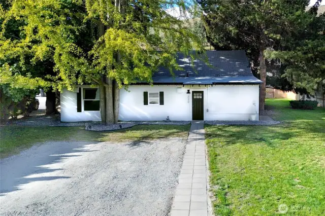 Large gravel driveway for RV, ATV, or boat parking and spacious lawn with a walkway to the Gibson entrance.