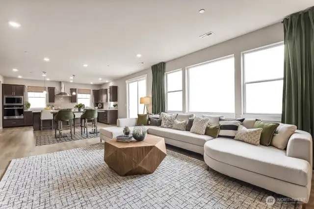 Open concept great room, informal dining area, breakfast bar, and large windows pouring in natural light. Photo is representational. Actual home is under construction and finishes will vary. See site agent for details.