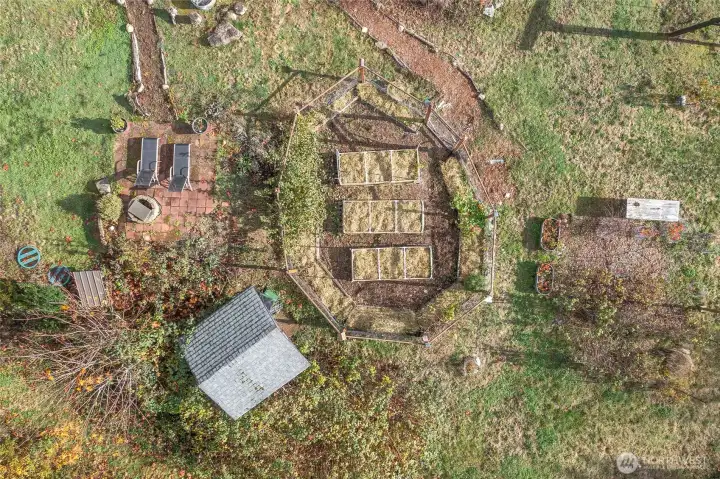 Fenced garden with raised beds, patio seating, and shed, all neatly cleaned and prepped for winter and ready for spring planting.