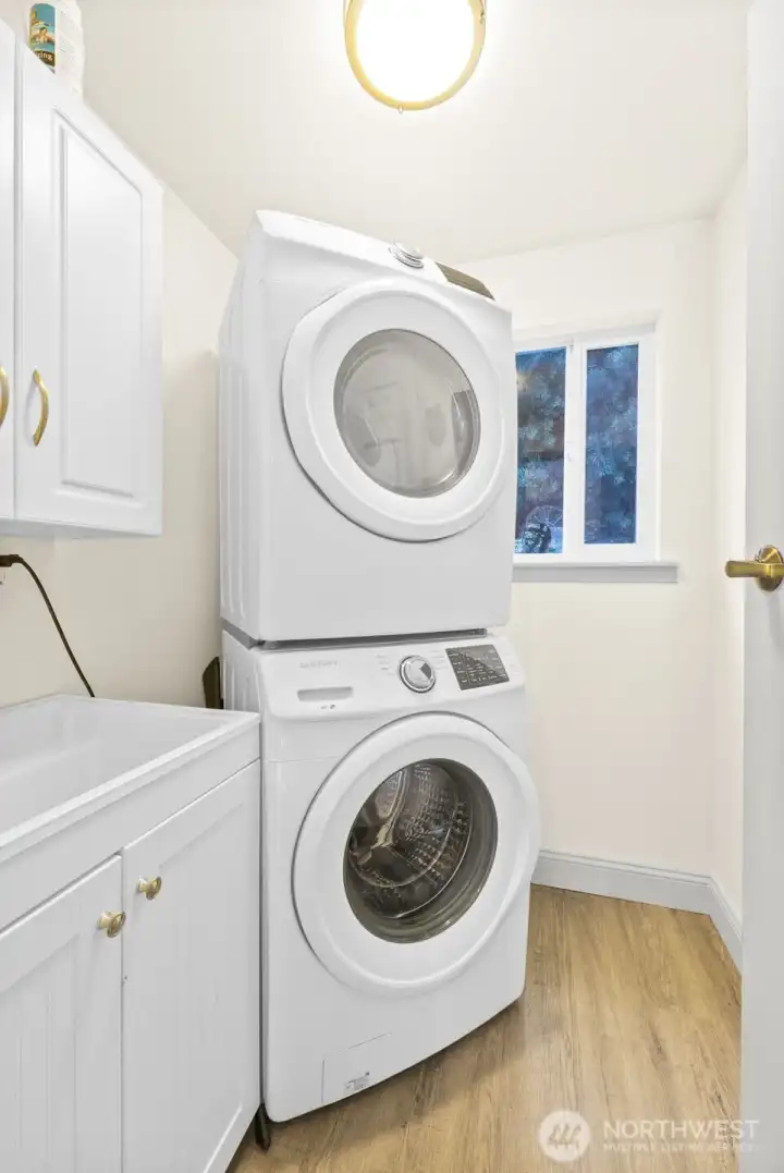 Laundry room to the right as you walk in main home entrance next to stairway to primary suite. Stacked Washer & Dryer to conserve space, storage for laundry and cleaning supplies, and Luxury Vinyl Plank flooring for easy cleaning.