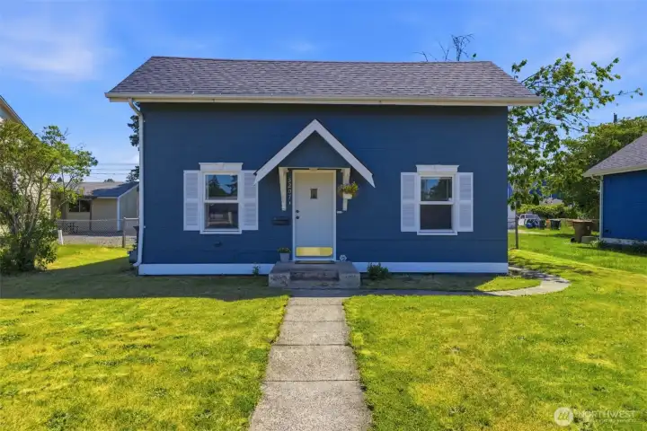 Welcoming curb appeal — Striking newly painted exterior with crisp white trim, a covered gabled entry, and a manicured front lawn with a classic walkway to the door.