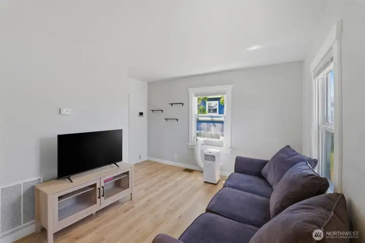 Light-filled living room — Open and airy main living space showcasing the newer luxury vinyl plank flooring and freshly painted walls.