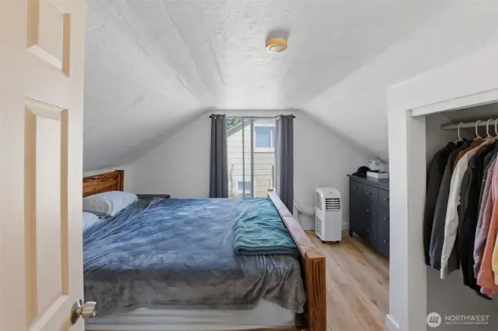 Upper-level bedroom — Cozy upstairs retreat with charming vaulted ceiling lines, a closet, and a sunny window.