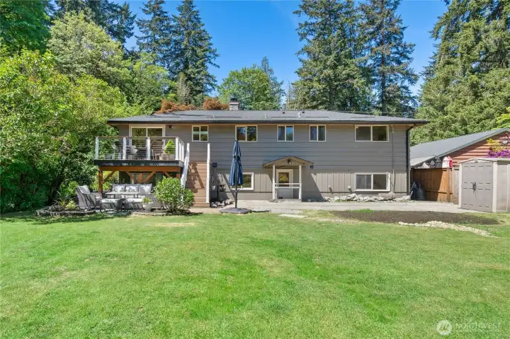 Back of home features deck with stairs to patio