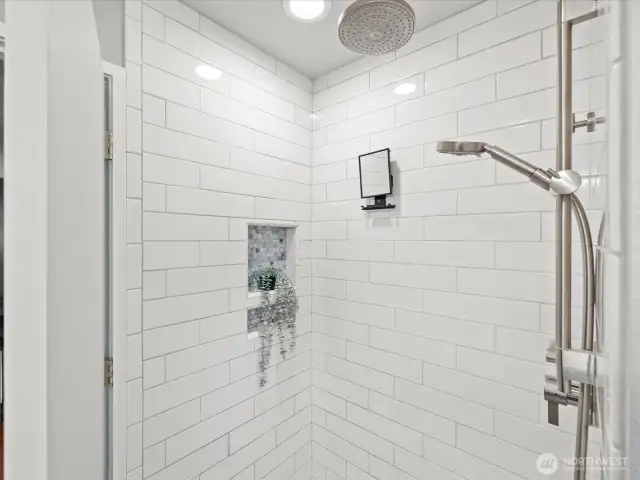 Main level walk in shower with rain shower head and separate handheld shower fixture.