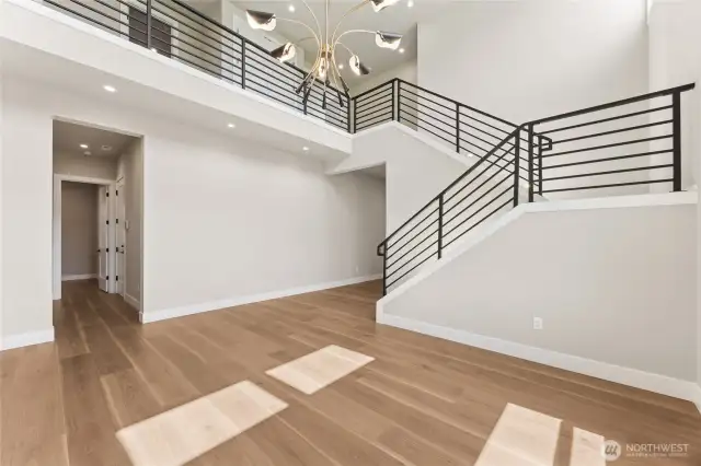Grand open-concept foyer with modern railing, chandelier lighting, and balcony overlook—ideal for showcasing contemporary Northwest architecture.