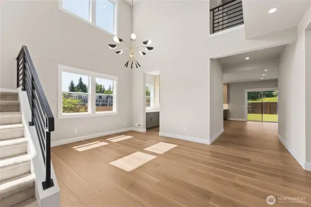 Soaring two-story foyer with modern light fixture, oversized windows, and natural hardwood flooring—designed to impress from the moment you step inside.